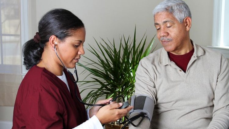 A hospice nurse takes a patient's blood pressure.