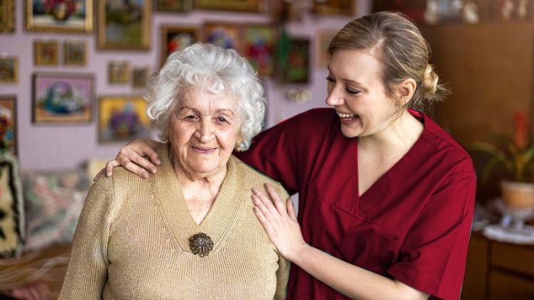 A hospice care nurse smiling at a patient who is happy in their home.
