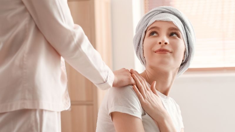 Teen girl wearing a head scarf looking up at someone placing a reassuring hand on her shoulder