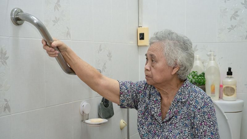 Older woman holding onto a grab bar in a bathroom