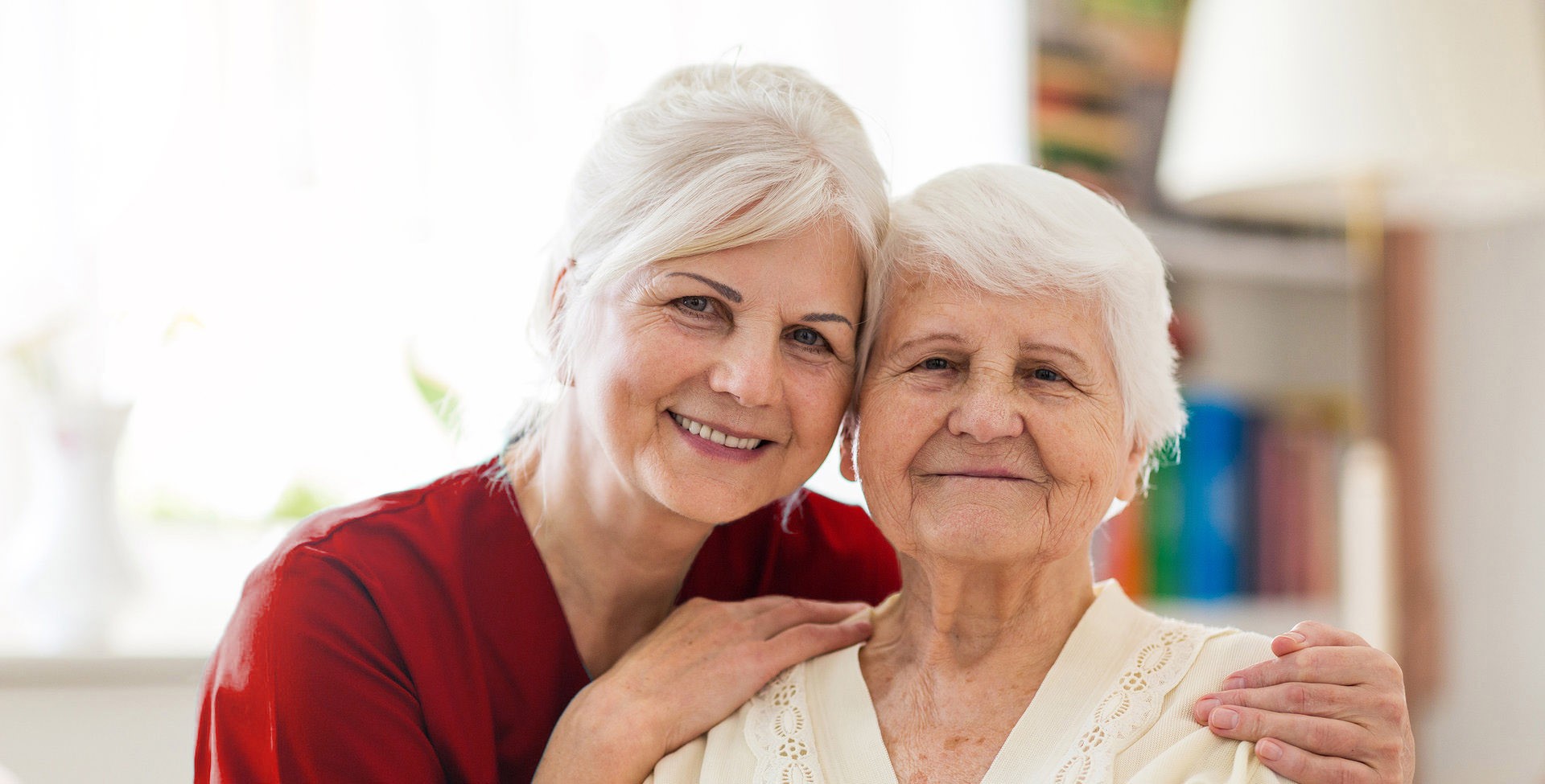 A nurse caregiver and an elderly patient smiling together.